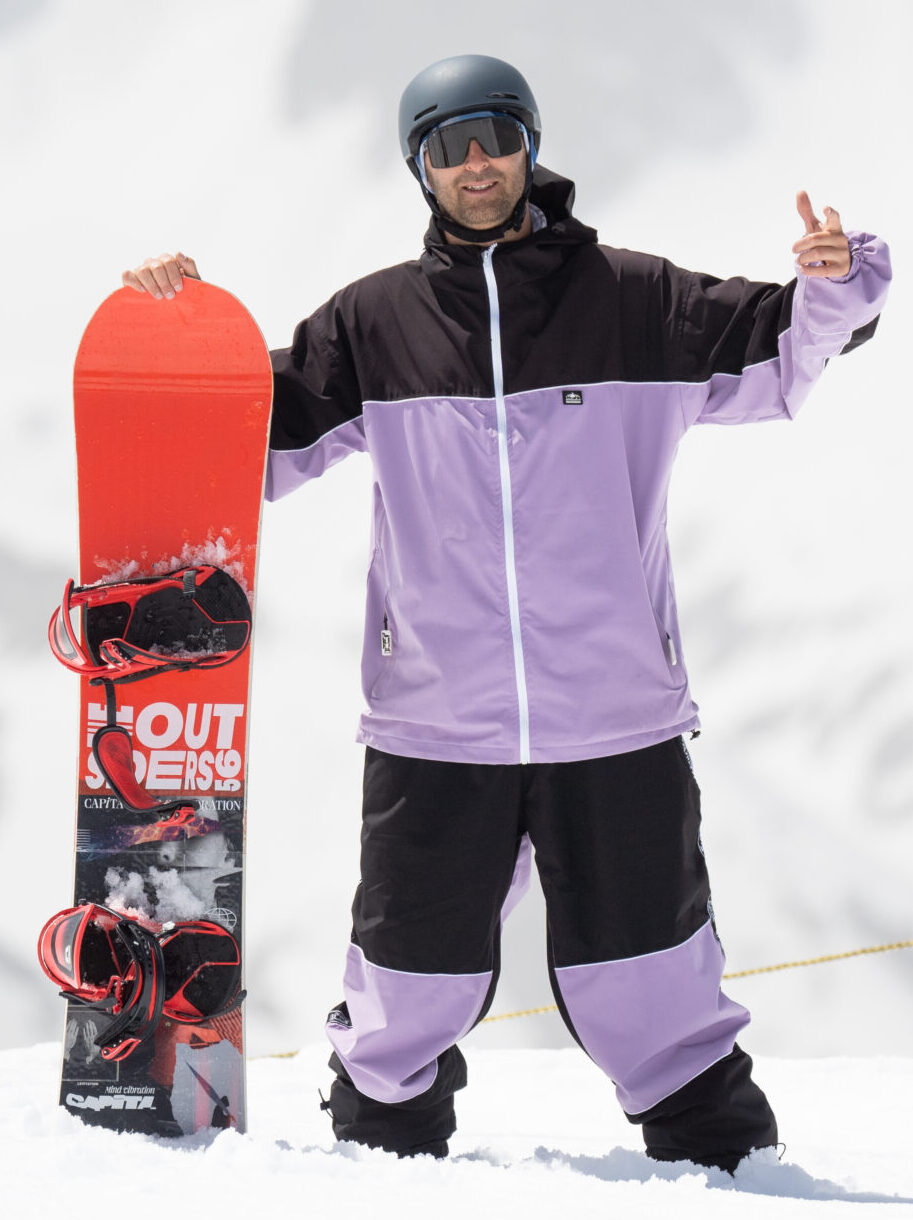 Icaro, membre de la team de moniteurs et rider freestyle aux 2 Alpes, posant avec sa planche rouge sur la neige