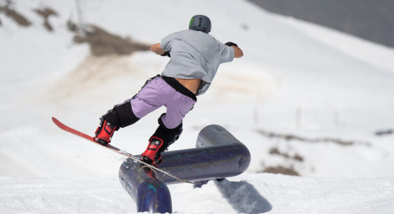 Snowboardeur en freestyle glissant sur un rail au snowpark des 2 Alpes