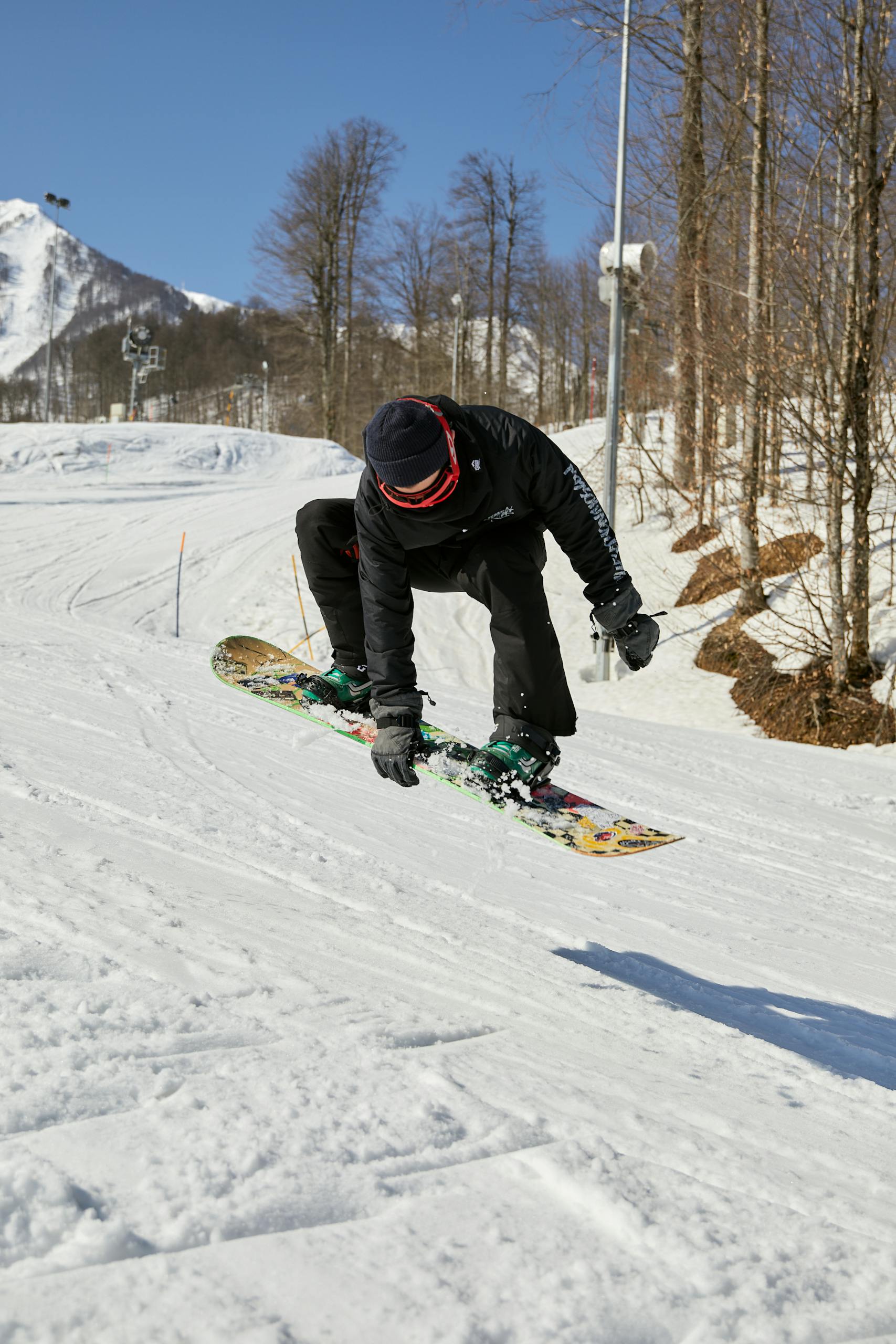 Exciting snowboarding stunt captured in winter landscape with snow-covered slopes and bare trees.