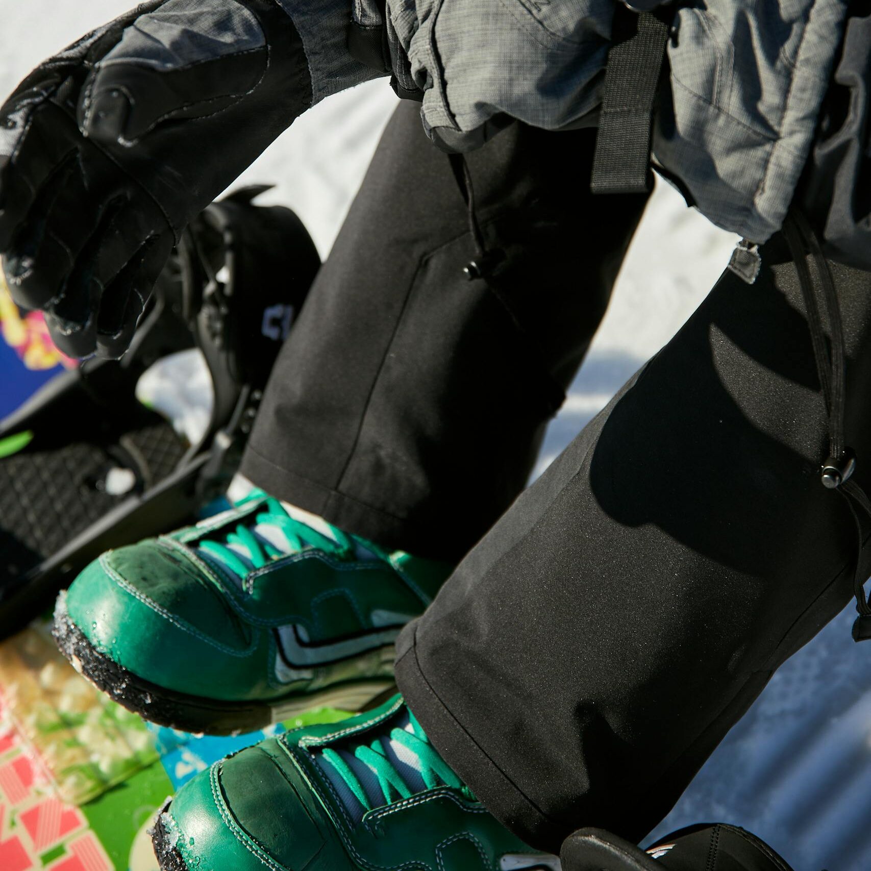 Snowboarder adjusting gloves, getting ready for a winter slope ride.