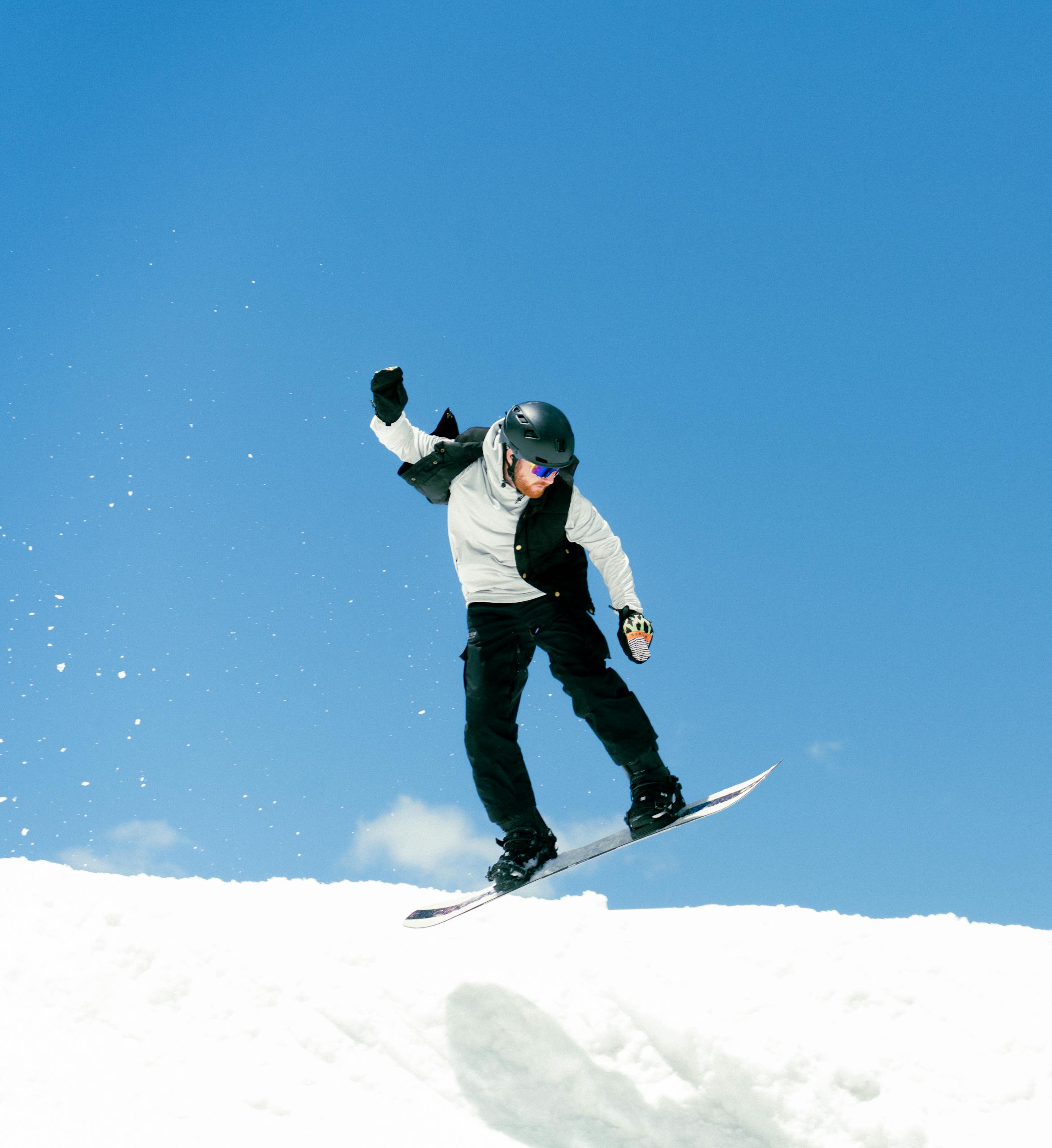 Snowboarder executing a trick under a clear blue sky at Brighton Resort, Utah.