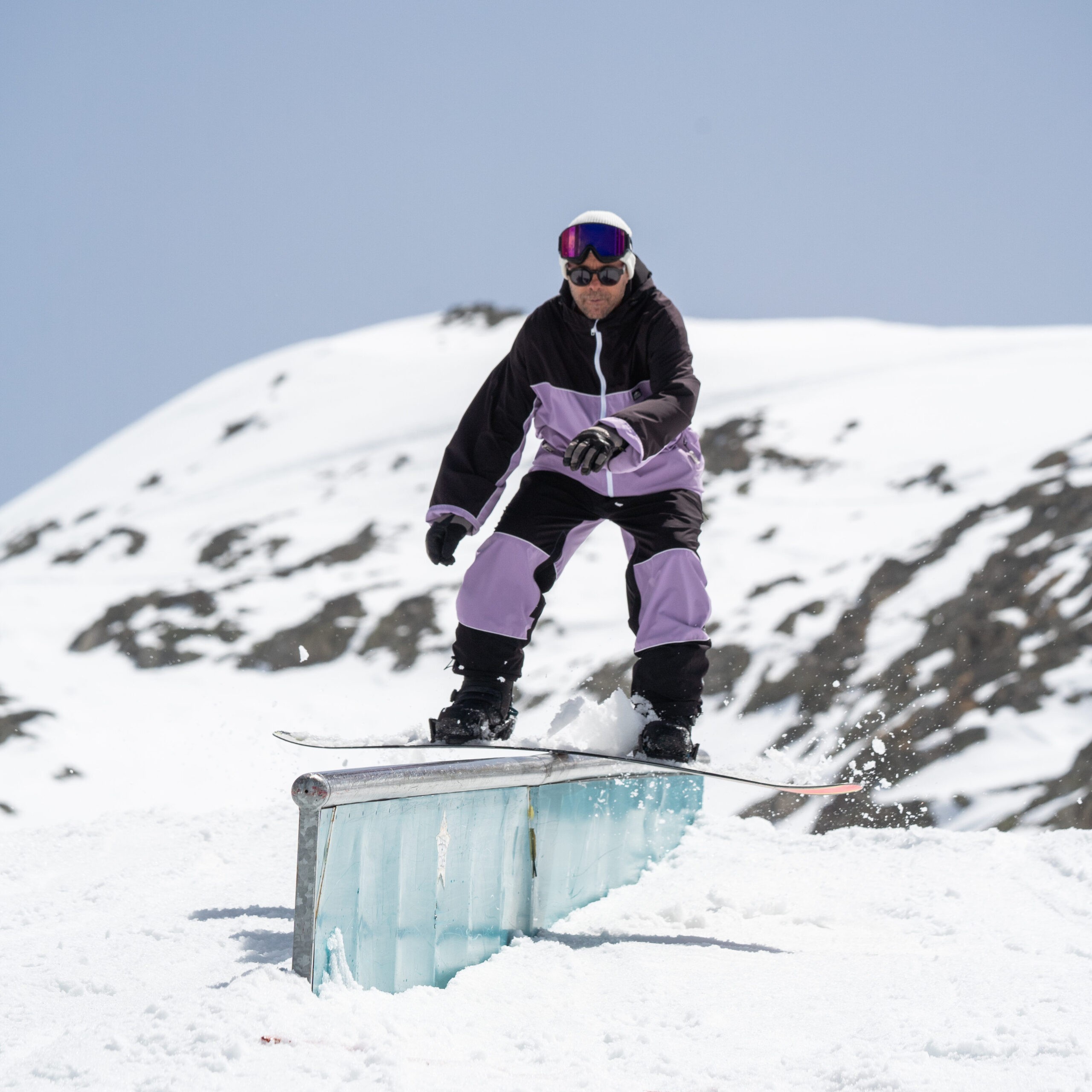 Snowboardeur en cours collectif de freestyle aux 2 Alpes glissant sur un module