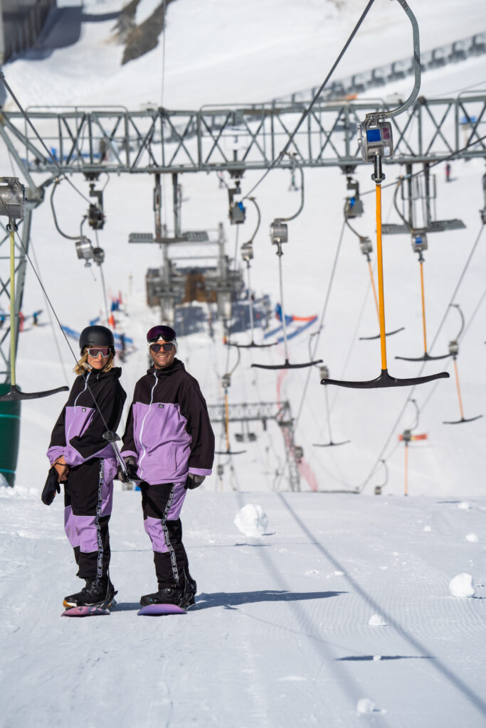 Deux snowboardeuses en tenue violette au départ du téléski aux 2 Alpes lors d’un shooting photo
