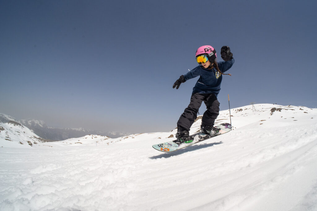 Enfant en snowboard réalisant un petit saut aux 2 Alpes – progression en cours enfants