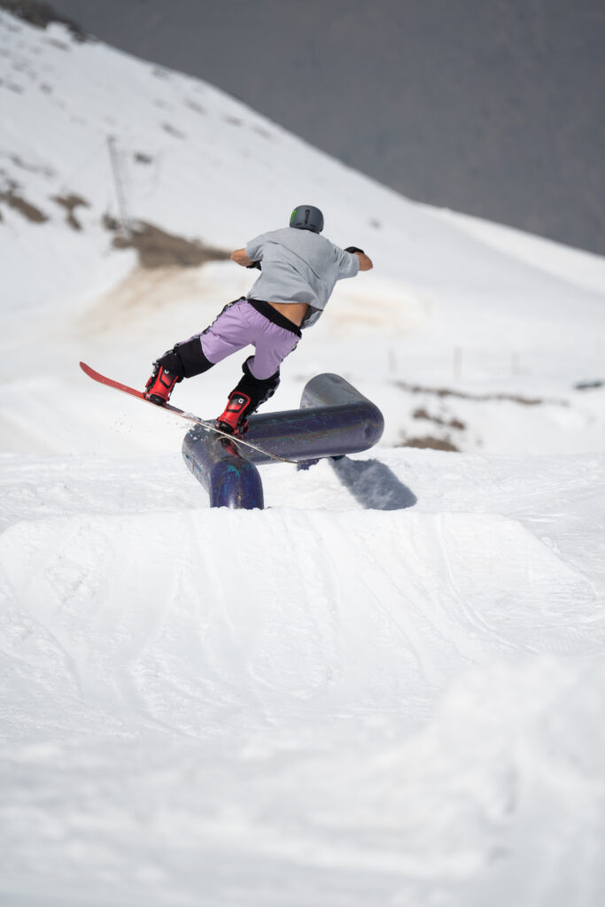 Snowboardeur en slide freestyle sur un rail courbé dans le snowpark des 2 Alpes
