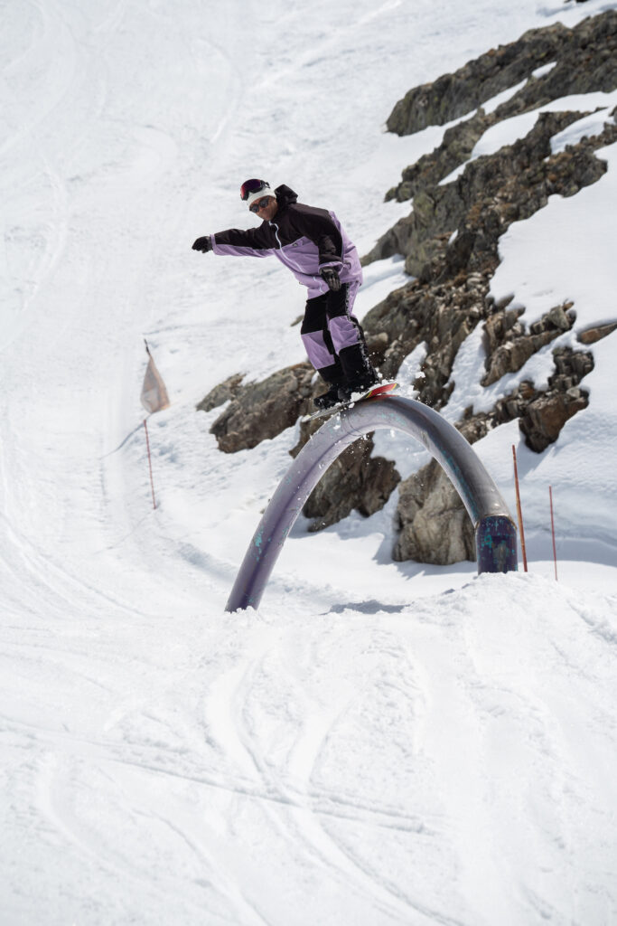 Snowboardeur en slide freestyle sur un rainbow rail dans le snowpark des 2 Alpes