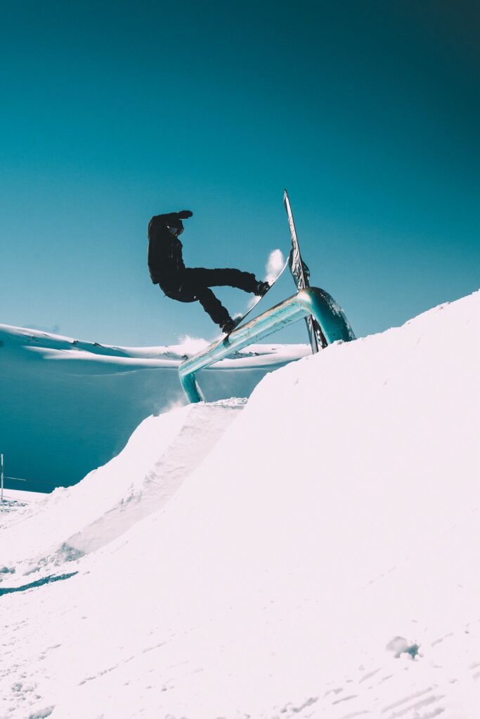 Snowboardeur en trick freestyle sur une barre métallique dans le snowpark