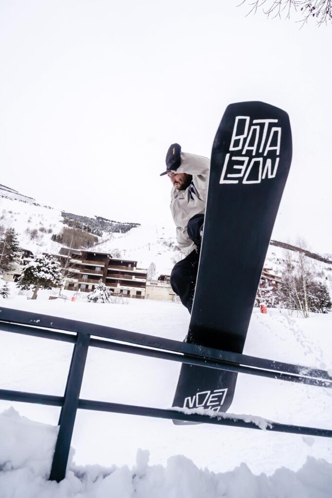 Snowboardeur en slide freestyle sur un rail Bataleon dans un snowpark