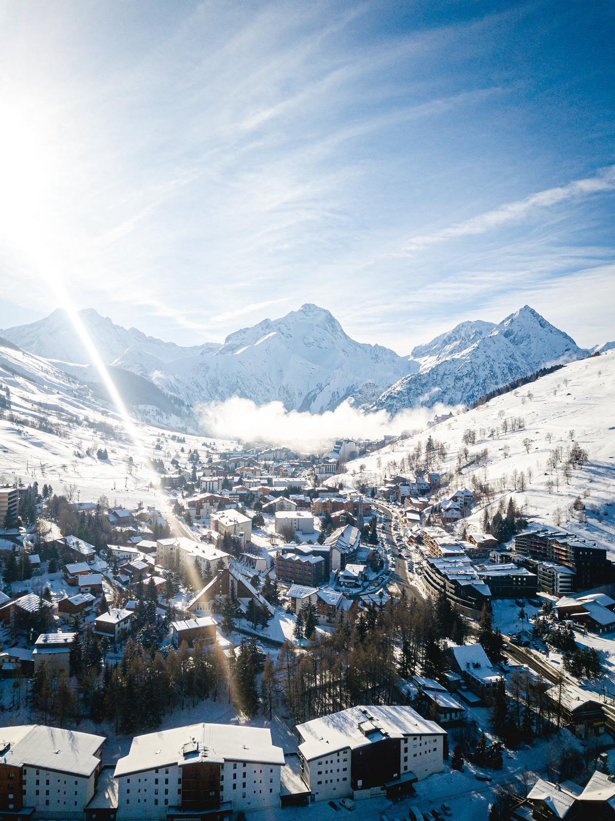Vue aérienne du village des 2 Alpes sous la neige avec les sommets alpins en arrière-plan