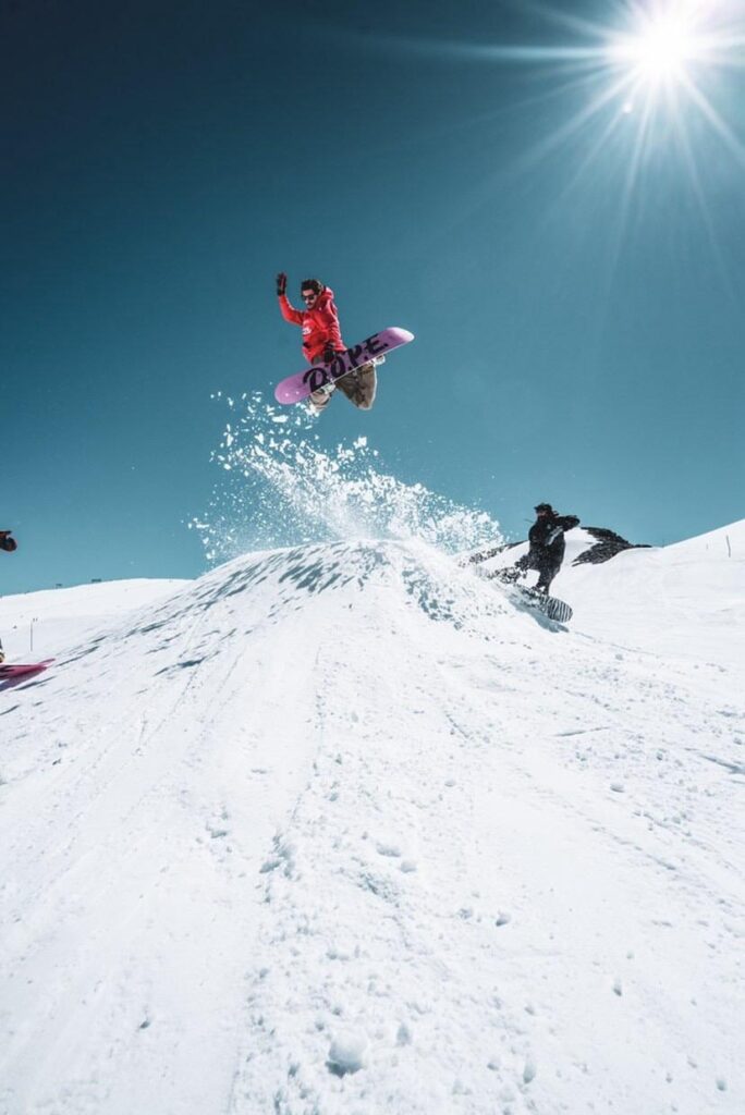 Snowboarder effectuant un saut sur un kicker aux 2 Alpes lors d’un shooting photo freestyle