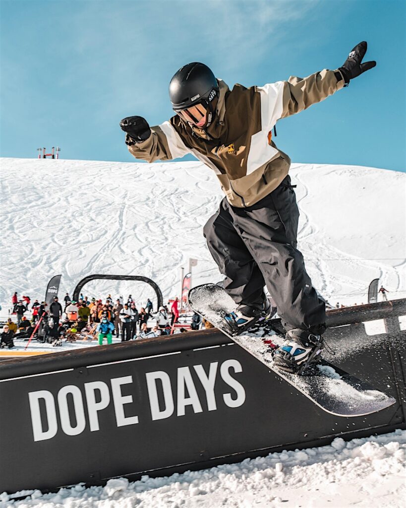 Snowboarder réalisant une figure sur un rail pendant un événement freestyle aux 2 Alpes.